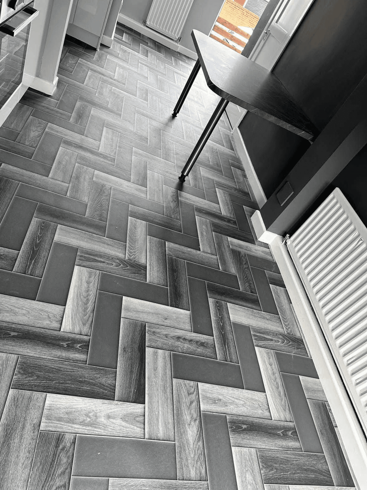 Grey wood-effect vinyl tiles laid in herringbone pattern in hallway