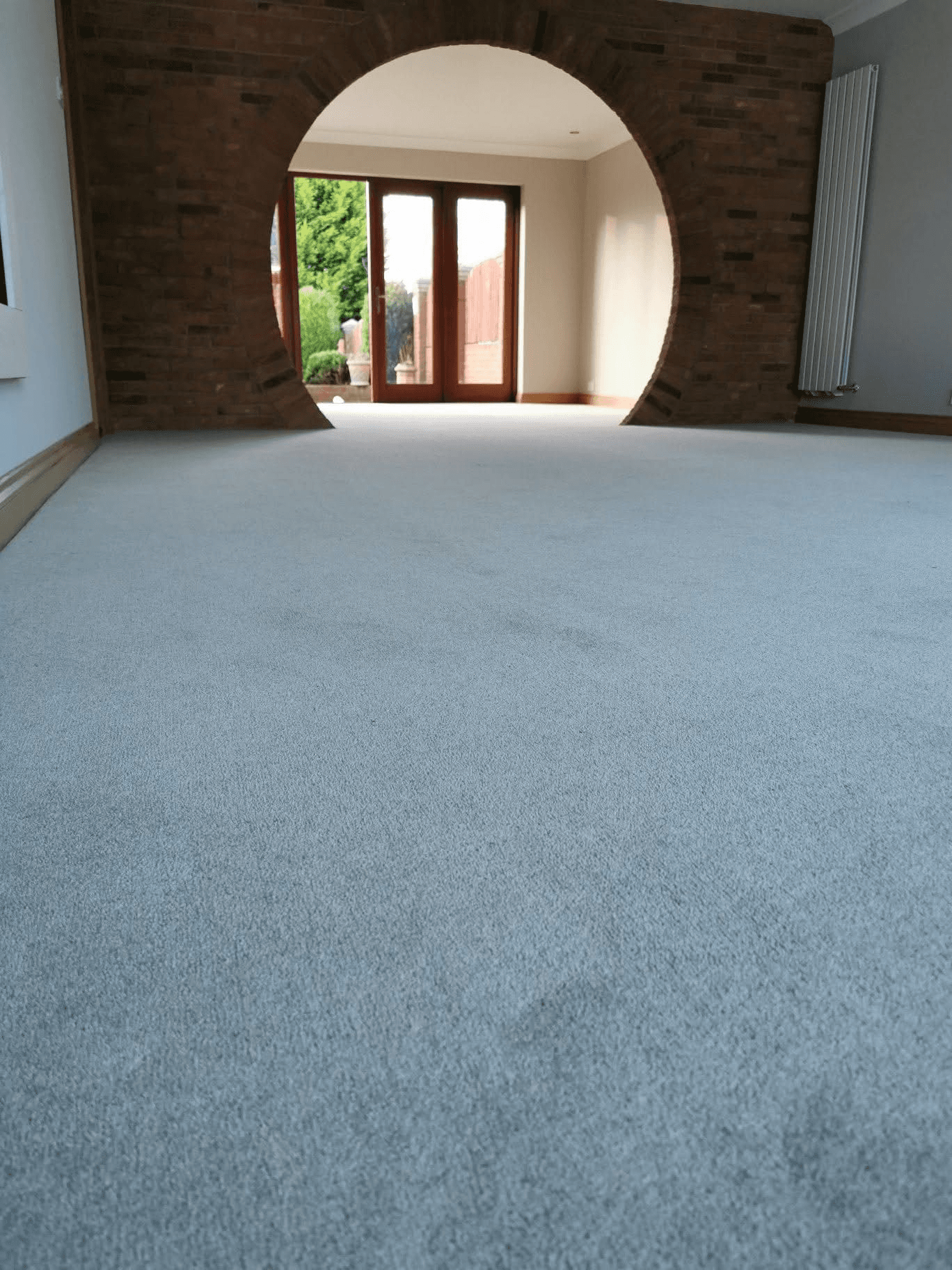 White plush carpet in open-plan living room with feature circular brick archway