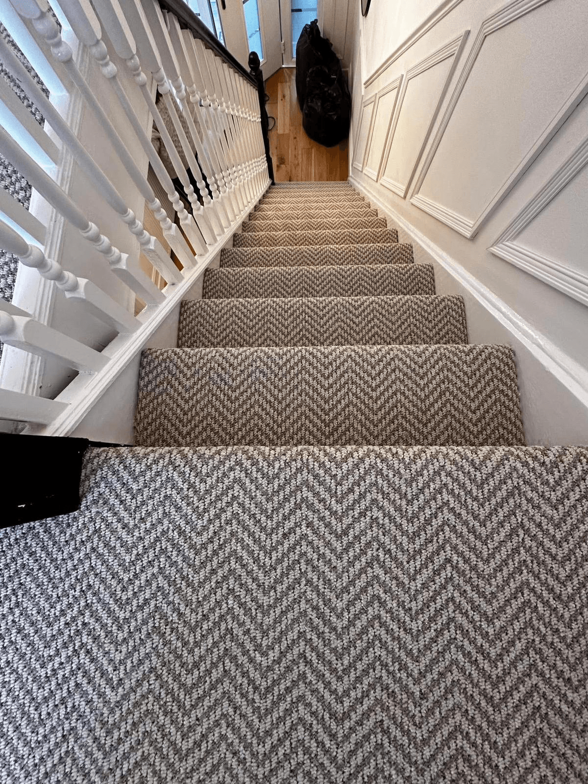 Grey herringbone woven carpet fitted on staircase with white painted spindles